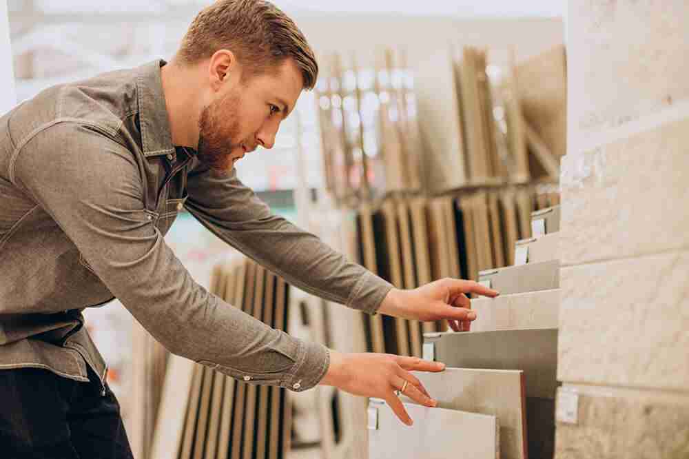 young-man-choosing-tiles-at-building-market1-scaled
